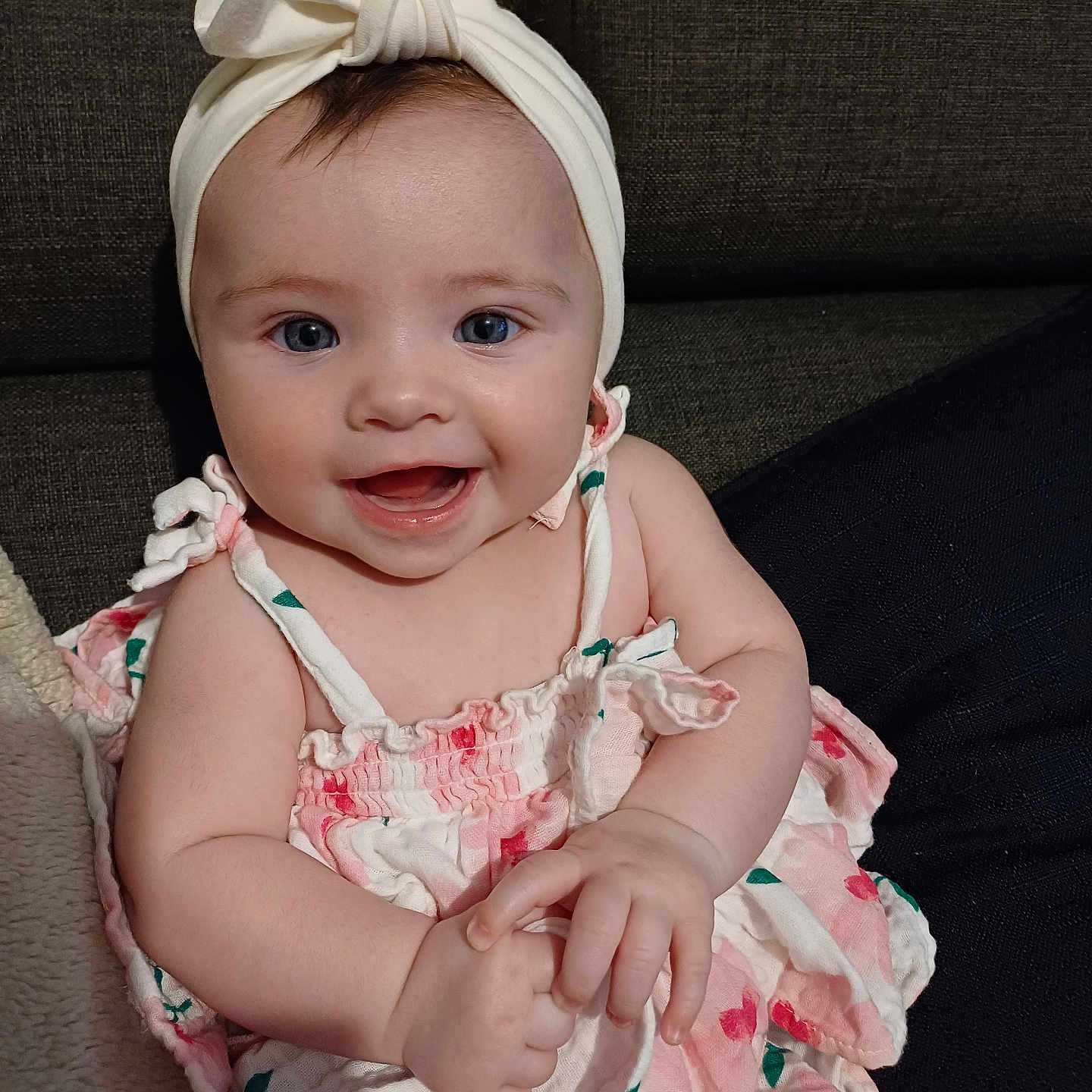 Willow is registered to the contest to win money with this photo: baby, blanket, blue_eyes, bow, child, couch, cute, dress, floral, hands, happy, headband, indoors, infant, person, portrait, sitting, skin, smiling, young