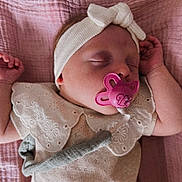 Emy participe au concours pour gagner de l'argent avec cette photo : baby, sleeping, pacifier, headband, blanket, pink, cream, clothing, infant, cute, peaceful, soft_texture, floral, embroidery, hand, face, portrait, indoors, child, toddler