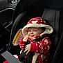 baby, car_seat, child, red_clothing, hooded_jacket, seatbelt, smile, indoor, infant, cute, patterned_clothing, safety, car_interior, face, person, seat, button, fabric, hands, warm_clothing