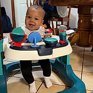 Donte joined the competition — help win amazing prizes! baby, walker, smiling, child, indoor, woman, phone, furniture, table, chair, tile_floor, toys, happy, person, glasses, home, family, casual, clothing, seated