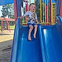 child, slide, playground, outdoor, barefoot, tshirt, blue, yellow, red, grass, trees, play_equipment, summer, fun, recreation, person, park, daylight, feet, happy