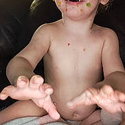 Ryden is registered to the contest to win money with this photo: toddler, child, face, hands, blanket, food, messy, indoor, couch, smiling, skin, curly_hair, cheerful, playful, person, baby, expression, seat, comfort, casual