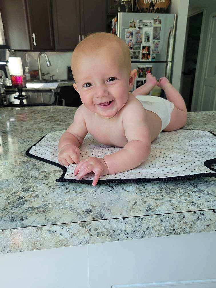 Briggs is registered to the contest to win money with this photo: baby, baby_toddler_clothing, cheek, child, eye, floor, flooring, foot, happy, hardwood, home_appliance, human_body, iris, joy, kitchen_appliance, person, room, sitting, skin, smile