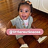baby, bows, child, clothing, curly_hair, cute, excited, fashion, flooring, happy, home, indoors, infant, person, portrait, shoes, sitting, smiling, social_media, wooden_floor
