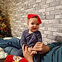 Victor participe au concours pour gagner de l'argent avec cette photo : baby, child, adult, hands, red_hat, blue_outfit, christmas_tree, holiday, indoor, brick_wall, smile, playful, person, cozy, holding, festive, toy, couch, family, warm