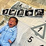 baby, infant, blue_onesie, yawning, blanket, ultrasound_images, floor_tiles, newborn, sleepy, lying_down, curly_hair, indoor, soft_lighting, cute, child, person, portrait, hand, feet, home