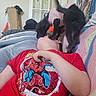 animal, black_dog, blanket, child, couch, cozy, dog, door, fun, glass_pane, home, indoor, interaction, lying_down, person, pet, playing, spiderman, stickers, tshirt