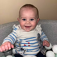 Lya a rejoint le concours — aidez-le/la à gagner de superbes lots ! baby, blue_eyes, bunny_print, child, clothing, cute, face, gray_chair, hand, happy, indoor, infant, person, play_balls, portrait, red_hearts, sitting, smiling, striped_shirt, young_child
