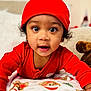 Reginald is registered to the contest to win money with this photo: baby, child, red_hat, red_clothing, blanket, teddy_bear_pattern, christmas_trees, indoor, portrait, curious, wide_eyes, close_up, cute, infant, cozy, holiday_theme, soft_texture, smiling, crawling, homedecor