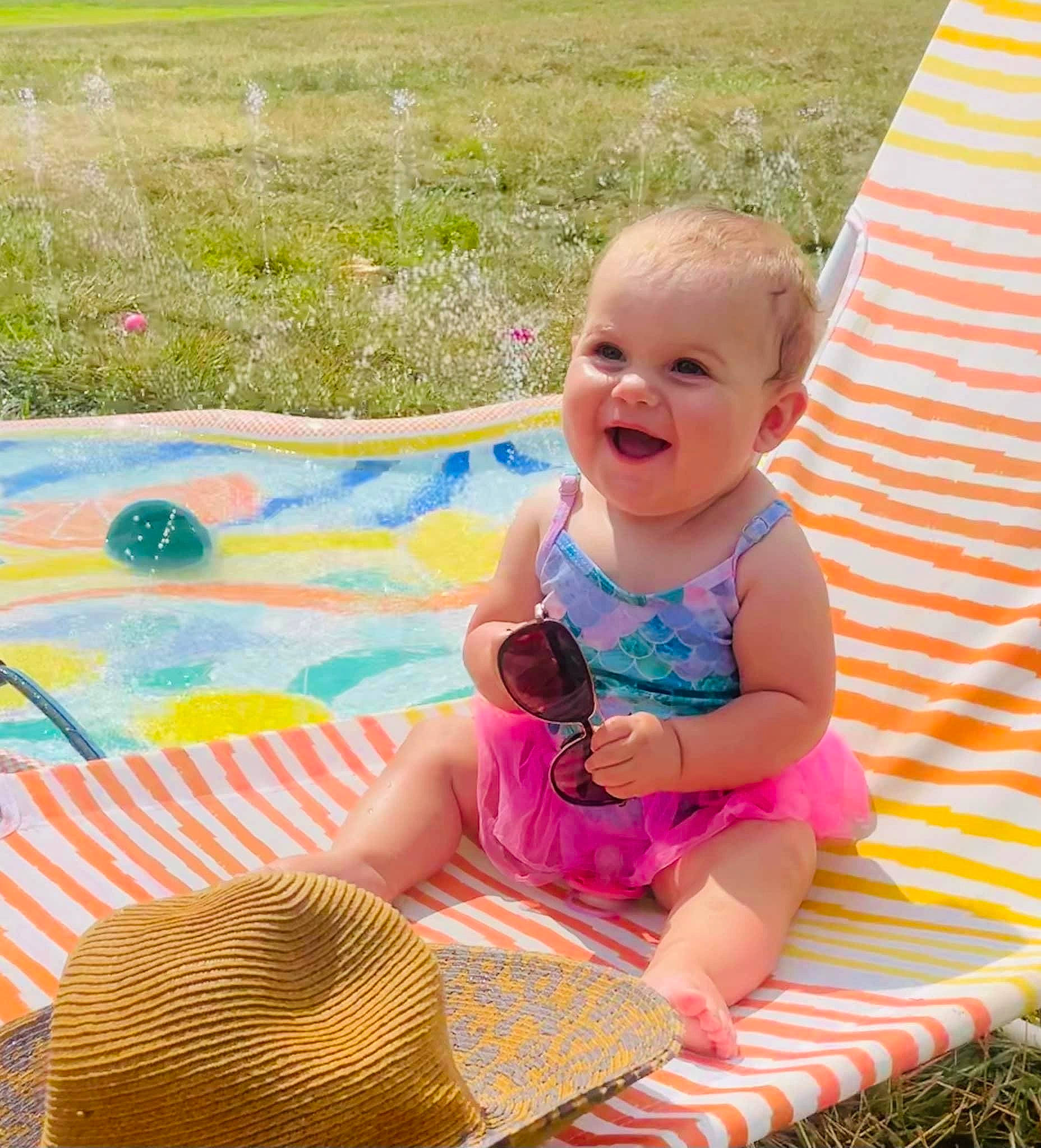 Bailey is registered to the contest to win money with this photo: baby, baby_toddler_clothing, child, event, fun, grass, happy, leisure, outdoor_furniture, pattern, people_in_nature, person, pink, plant, play, recreation, sitting, smile, summer, toddler