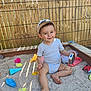 barefoot, child, colorful, happy, hat, metal_pot, outdoor, plastic_fork, play, sand, sandbox, shadow, short_sleeve_shirt, smile, summer, sunlight, toddler, toy, wire_mesh, wooden_fence