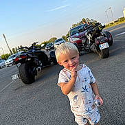 Lemon a rejoint le concours — aidez-le/la à gagner de superbes lots ! child, toddler, blond_hair, smiling, parking_lot, motorcycle, car, pajamas, shorts, sneakers, outdoor, daytime, asphalt, blue_sky, vehicle, cute, person, holding_object, casual_clothing, playful