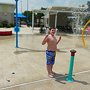 Mycah is registered to the contest to win money with this photo: child, boy, water_park, splash_pad, swim_trunks, pokemon, water_spray, barefoot, outdoor, summer, playground, fun, park, concrete, daylight, blue, toy, casual, happy, water