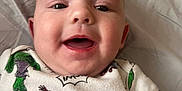 Khaison joined the competition — help win amazing prizes! baby, child, smile, face, superhero, shirt, bed, sheet, happy, lying_down, infant, clothing, closeup, person, cute, skin, expression, young, casual, indoor
