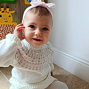 Lina a rejoint le concours — aidez-le/la à gagner de superbes lots ! baby, child, girl, headband, bow, white_sweater, tights, floor, smile, face, indoor, playful, hand, cute, portrait, giraffe_art, colorful_background, wall_art, cozy, seated