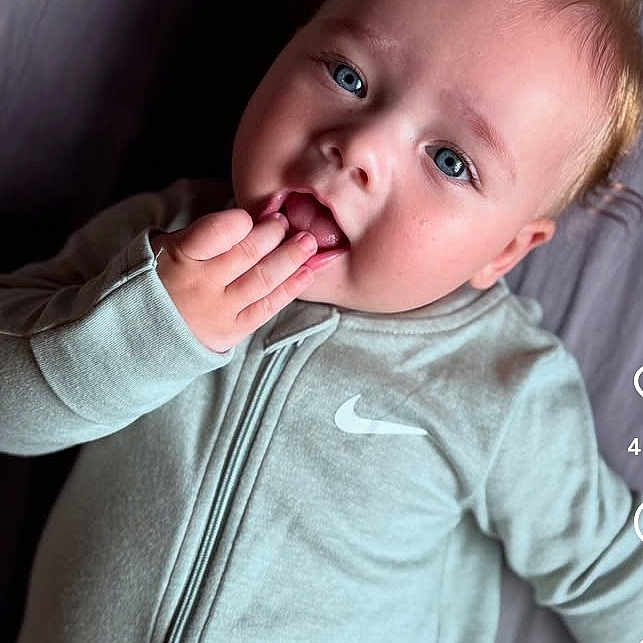 Joris a rejoint le concours — aidez-le/la à gagner de superbes lots ! baby, blonde_hair, blue_eyes, child, closeup, clothing, cute, expression, face, hand, indoor, infant, lying_down, nike_logo, person, playful, portrait, skin, young_child, zip_up