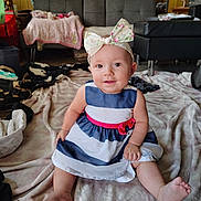Eleeah is registered to the contest to win money with this photo: baby, child, girl, bow, dress, striped_dress, pink, blue, blanket, sitting, smiling, indoors, living_room, furniture, couch, carpet, floor, cute, headwear, happy