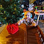 baby, child, christmas_tree, table, wood, toy, indoor, holiday, decorations, lights, carpet, sweater, person, face, furniture, plush, play_area, blanket, seat, curious