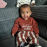 Adonis joined the competition — help win amazing prizes! toddler, child, smiling, sitting, clothing, sweater, striped_pants, shoes, couch, pillows, blanket, indoor, happy, cute, baby, face, person, furniture, cozy, home
