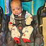 baby, car_seat, infant, onesie, mittens, star_pattern, straps, safety_harness, geometric_pattern, fabric, child, seat, floor, indoor, cute, small, newborn, person, clothing, resting