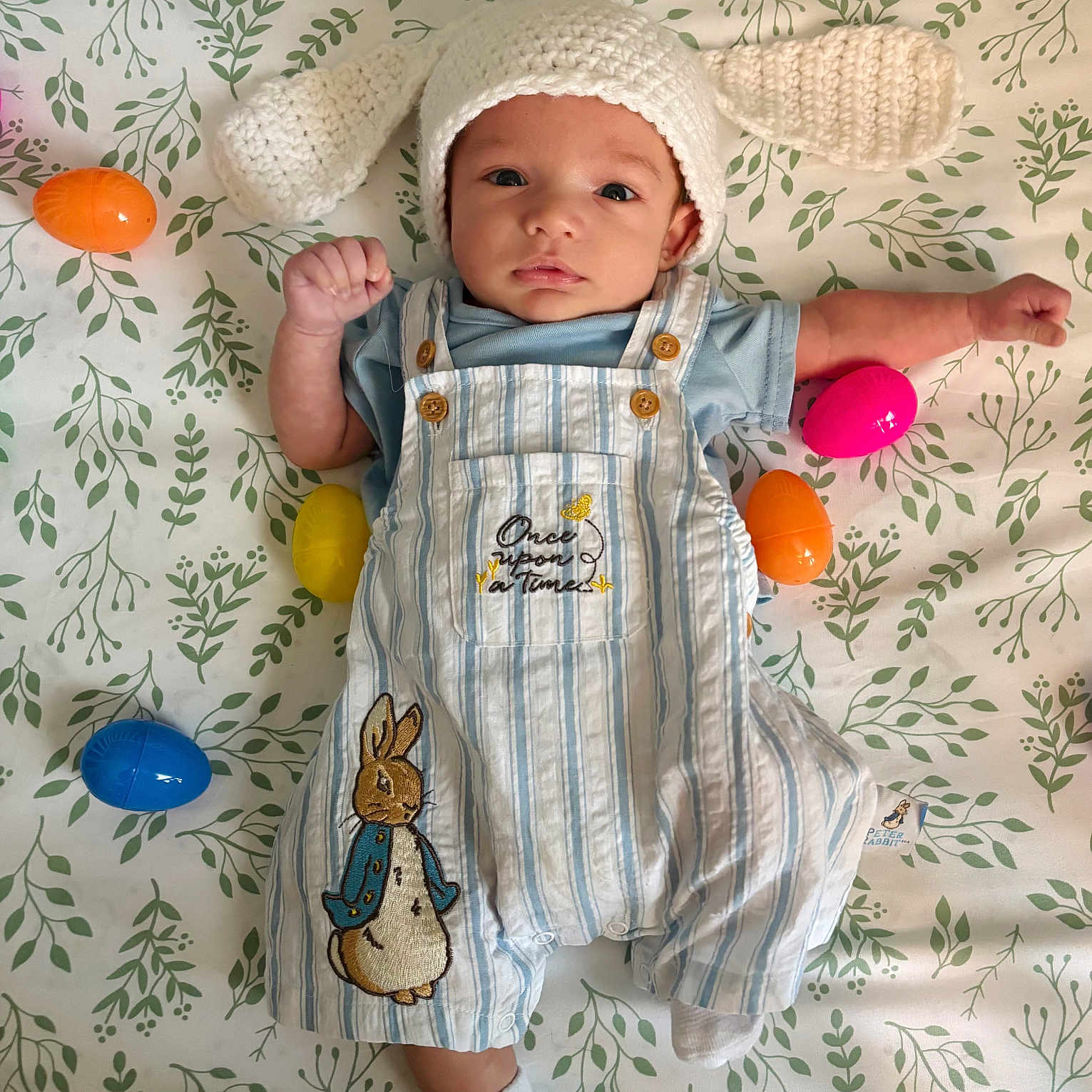 Waylon is registered to the contest to win money with this photo: applique, baby, beanie, bed, bodypart, bonnet, cap, clothing, face, finger, glove, hand, hat, head, newborn, pants, pattern, person, photography, portrait