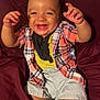 baby, child, smiling, laughing, plaid_shirt, yellow_shirt, shorts, barefoot, sitting, couch, maroon, indoor, happy, joyful, arms_raised, infant, cute, portrait, person, clothing