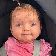 Ariane a rejoint le concours — aidez-le/la à gagner de superbes lots ! baby, child, girl, car_seat, pink_shirt, pony_tail, blue_eyes, smile, face, infant, clothing, seatbelt, cute, person, portrait, young_child, hair, expression, sitting, indoor