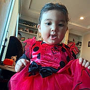Natalia Segura is registered to the contest to win money with this photo: toddler, child, costume, ladybug, red_dress, black_polka_dots, indoor, home, table, pumpkin, plush_toy, curtains, light, ceiling, smiling, cute, clothing, person, portrait, playful