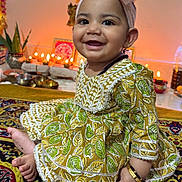 Vamika joined the competition — help win amazing prizes! baby, child, smiling, headband, dress, patterned_clothing, carpet, indoors, decorations, candles, festive, happy, cute, jewelry, bracelet, sitting, portrait, celebration, colorful, infant