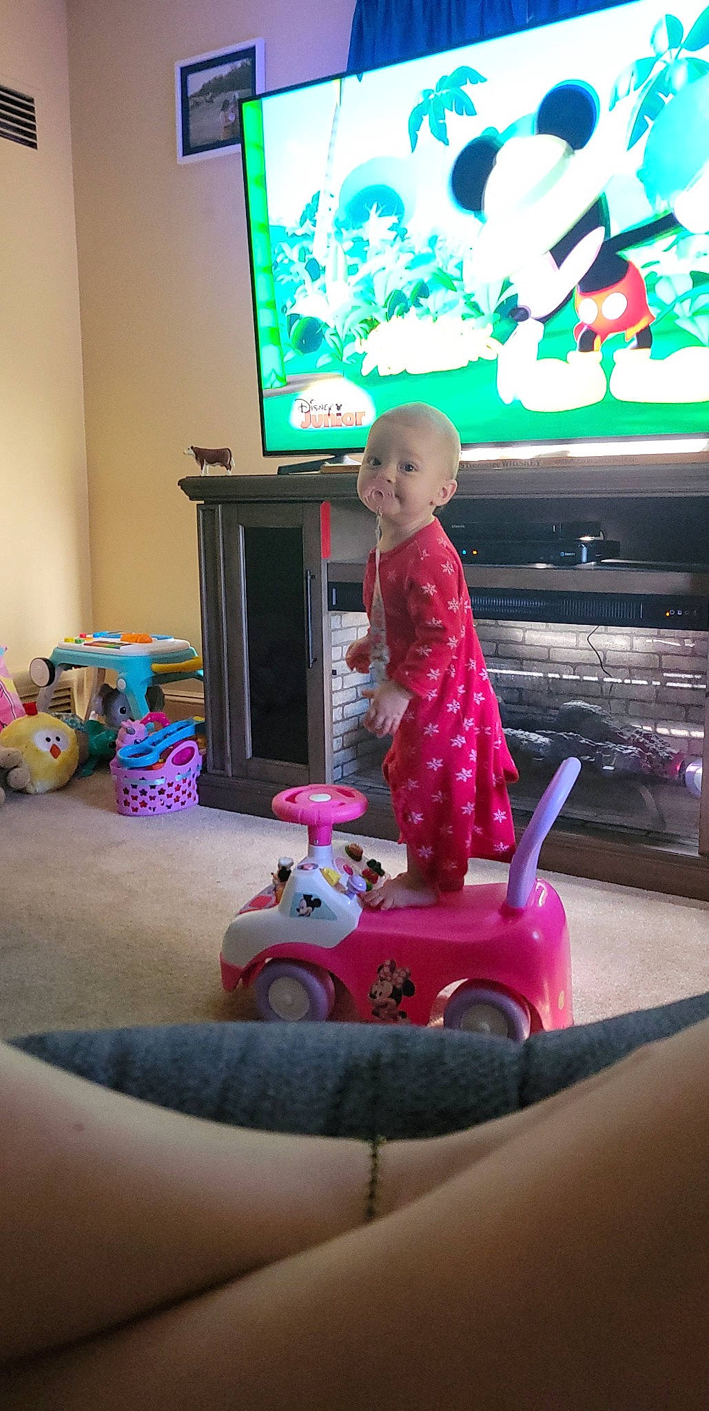 Carsyn is registered to the contest to win money with this photo: baby, child, display_device, electronic_device, flooring, fun, leisure, magenta, person, pink, play, purple, riding_toy, sitting, snapshot, television_set, tire, toddler, toy, toy_vehicle