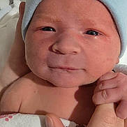 Hudson is registered to the contest to win money with this photo: baby, newborn, infant, blue_beanie, hat, blanket, hand, holding_hand, nursery_bed, hospital, face, eyes, skin, portrait, closeup, swaddled, cute, smile, bundle, cozy