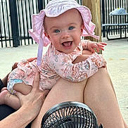 Oakley Grace is registered to the contest to win money with this photo: baby, infant, smiling, hat, pink_clothing, outdoor, legs, hand, fan, picnic_table, fence, sunhat, happy, person, skin, summer, daylight, playful, child, cute