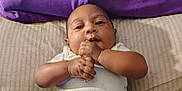 Ry'Lynn is registered to the contest to win money with this photo: baby, infant, child, bed, pillow, purple, onesie, clothing, hands, face, skin, lying_down, striped, cute, young, portrait, indoors, resting, person, soft