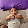 baby, infant, child, bed, pillow, purple, onesie, clothing, hands, face, skin, lying_down, striped, cute, young, portrait, indoors, resting, person, soft
