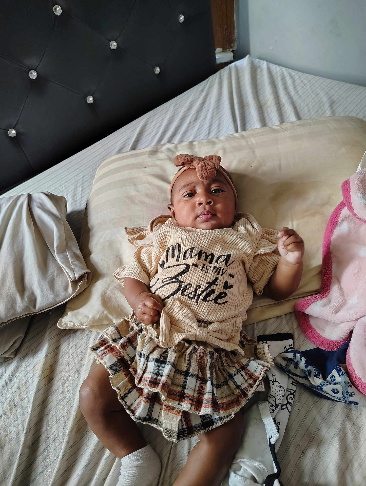 Ry'Lynn joined the competition — help win amazing prizes! baby, infant, bed, pillow, blanket, headband, bow, shirt, plaid_skirt, socks, sleepwear, indoors, child, person, cute, lying_down, cozy, furniture, text_on_clothing, portrait