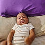 Ry'Lynn is registered to the contest to win money with this photo: baby, infant, child, onesie, bed, pillow, purple_pillow, smile, relaxed, skin, hand, foot, lying_down, striped_bed_sheet, cute, indoor, person, young, sleepwear, playful