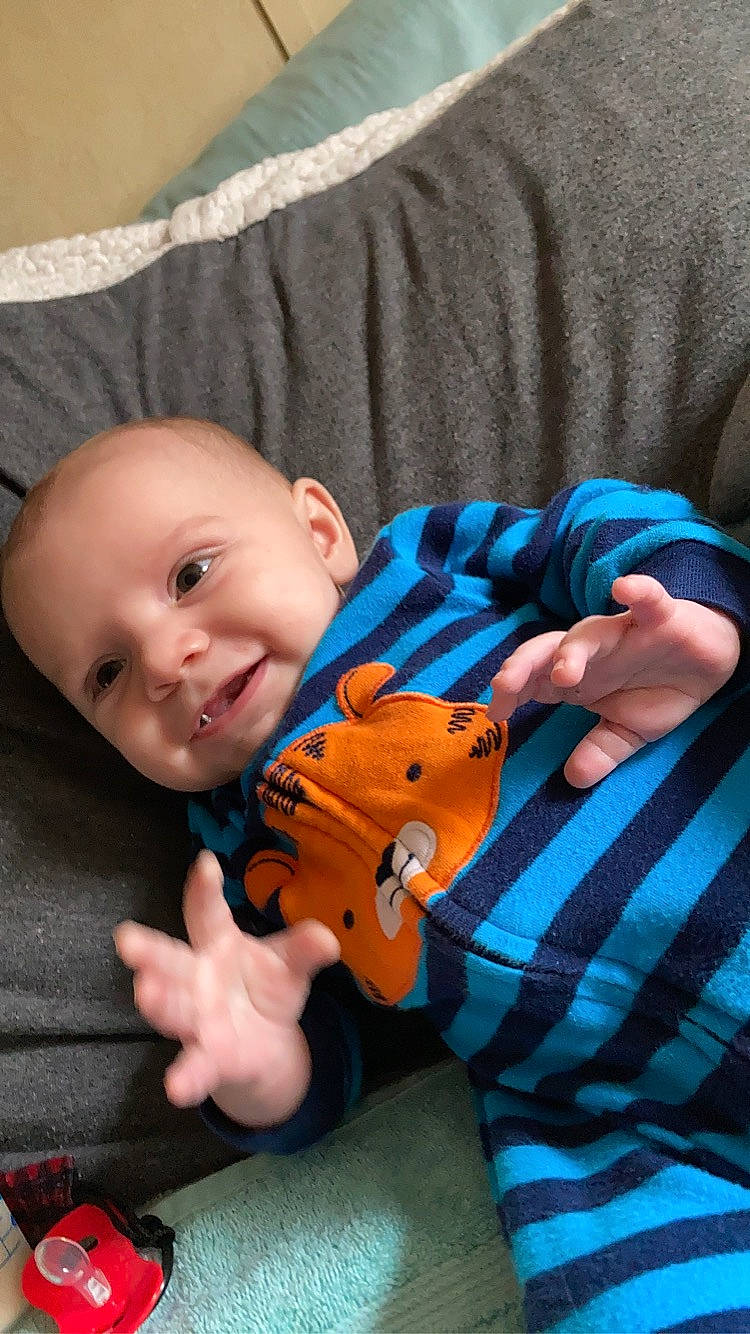 Liam is registered to the contest to win money with this photo: arm, baby, baby_toddler_clothing, cheek, child, comfort, finger, hand, happy, joy, nail, nose, orange, person, red, skin, sleeve, smile, thumb, toddler