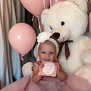 Jannah a rejoint le concours — aidez-le/la à gagner de superbes lots ! baby, balloon, celebration, child, cute, decor, dress, flower, happy, headband, indoor, infant, person, pink_balloon, pink_dress, portrait, sitting, smiling, teddy_bear, toy