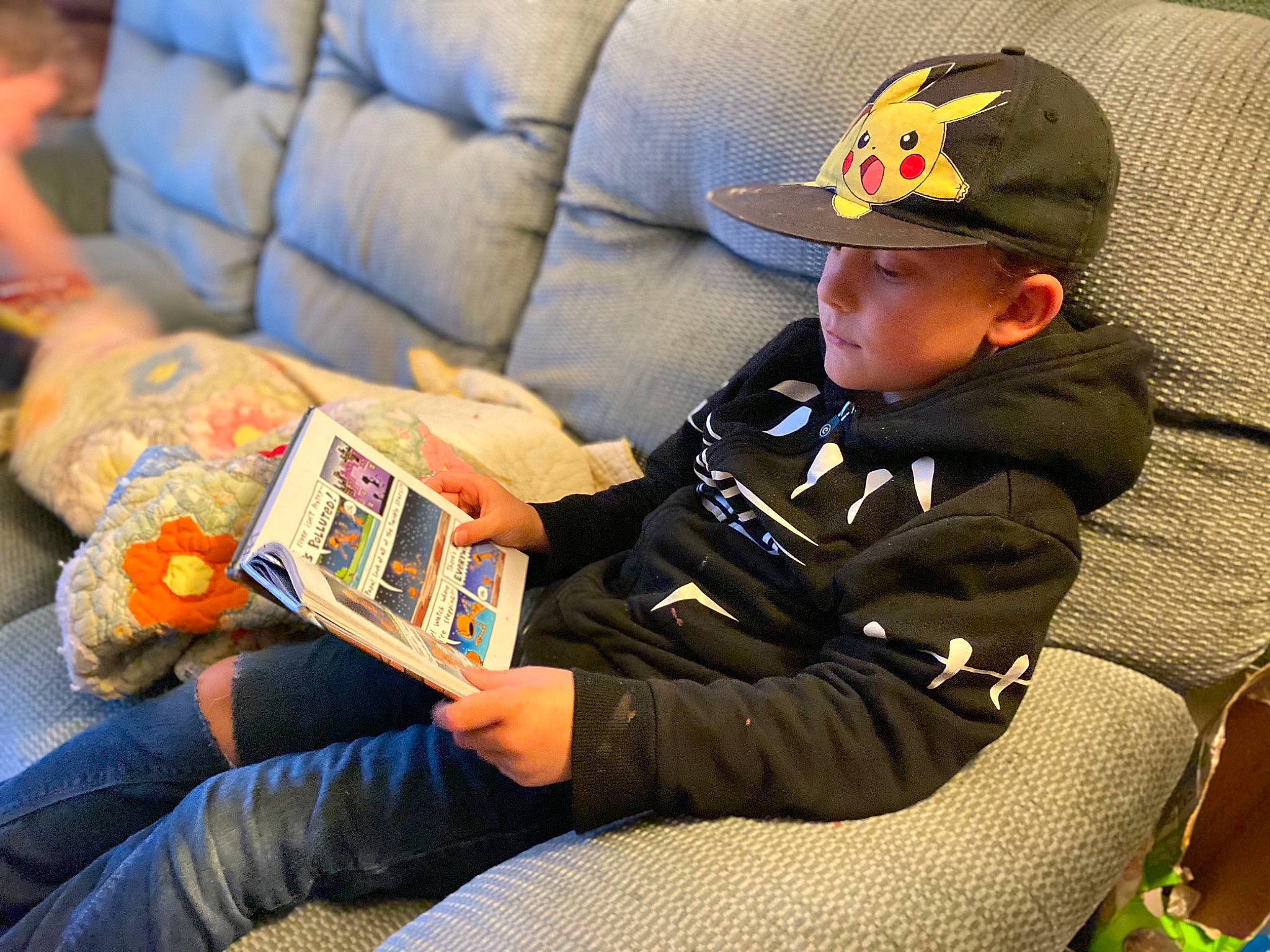 Brody joined the competition — help win amazing prizes! baseball_cap, cap, child, comfort, couch, fun, gadget, games, hat, headwear, lap, leisure, mammal, person, personal_protective_equipment, play, recreation, sharing, sitting, toddler