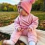 Aria is registered to the contest to win money with this photo: baby, child, pink_clothing, pink_hat, pom_pom_hat, socks, leaf, blanket, grass, autumn_leaves, outdoor, park, trees, fall, nature, side_profile, cute, infant, sitting, daylight