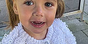 River is registered to the contest to win money with this photo: blonde_hair, blue_eyes, casual_clothing, child, closeup, cute, daylight, face, girl, happy, knitwear, mesh_screen, outdoor, pavement, person, pigtails, portrait, smiling, white_sweater, young_child