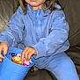 child, girl, blue_outfit, scrunchie, toy_bucket, toys, indoor, couch, playing, hands, brown_hair, casual_clothing, focused, young_child, sitting, home, leisure, cute, face, expression