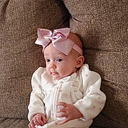 Karoleena is registered to the contest to win money with this photo: baby, infant, bow, headband, white_outfit, pink, couch, seated, cozy, cute, child, indoor, portrait, young_child, soft_fabric, clothing, hands, face, expression, comfort