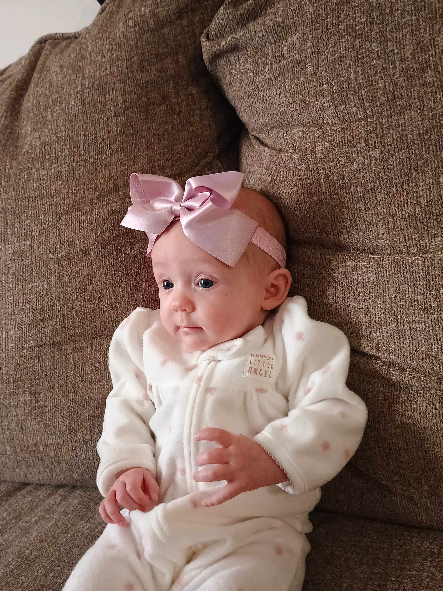 Karoleena is registered to the contest to win money with this photo: baby, infant, bow, headband, white_outfit, pink, couch, seated, cozy, cute, child, indoor, portrait, young_child, soft_fabric, clothing, hands, face, expression, comfort