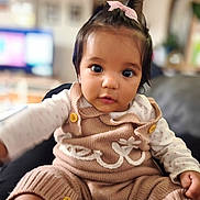 Chloé a rejoint le concours — aidez-le/la à gagner de superbes lots ! baby, child, infant, cute, knitted_overalls, pink_bow, indoor, portrait, face, eyes, button, sitting, cozy, clothing, person, young_child, cute_expression, home, soft_lighting, closeup