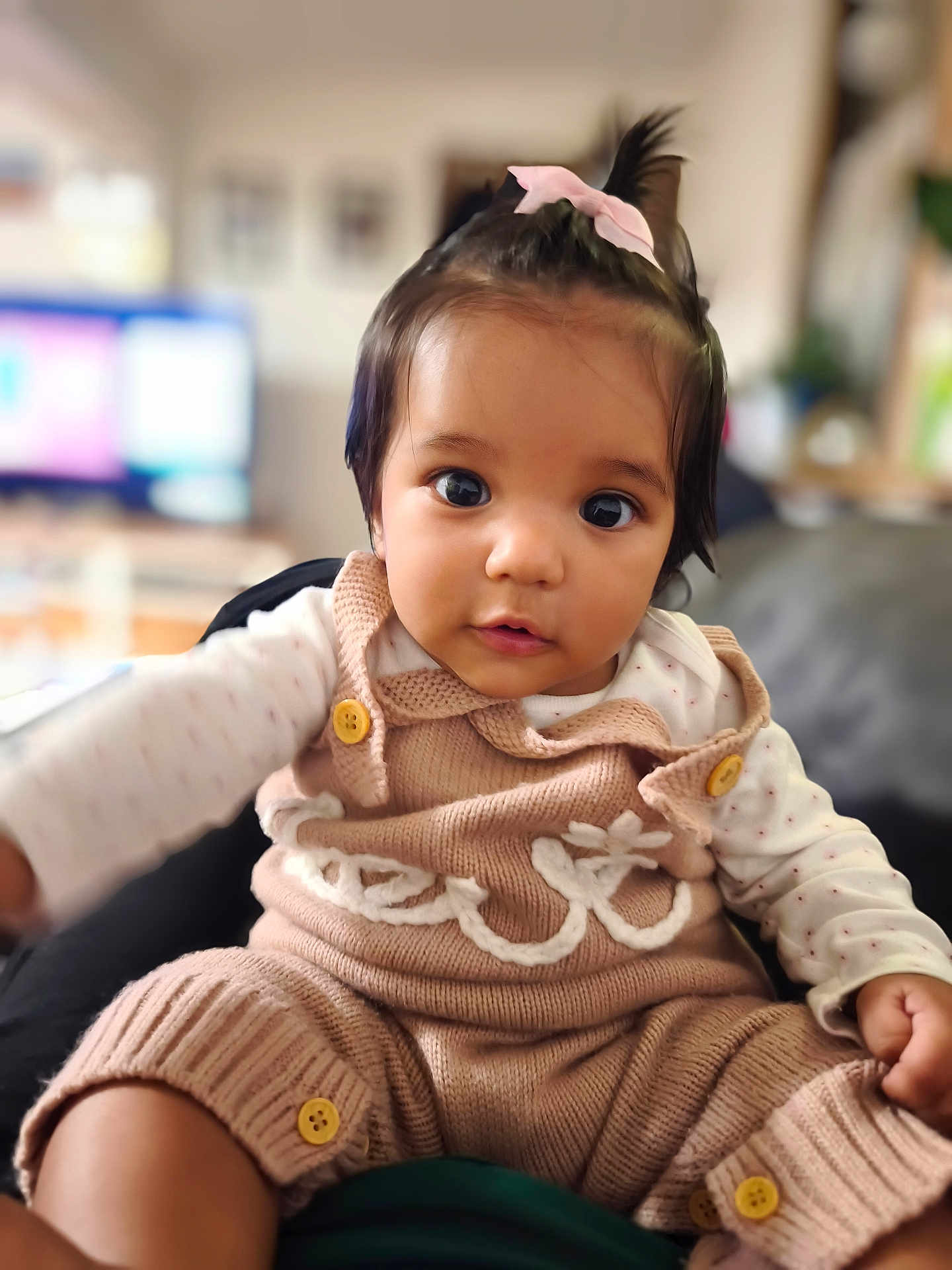 Chloé a rejoint le concours — aidez-le/la à gagner de superbes lots ! baby, child, infant, cute, knitted_overalls, pink_bow, indoor, portrait, face, eyes, button, sitting, cozy, clothing, person, young_child, cute_expression, home, soft_lighting, closeup