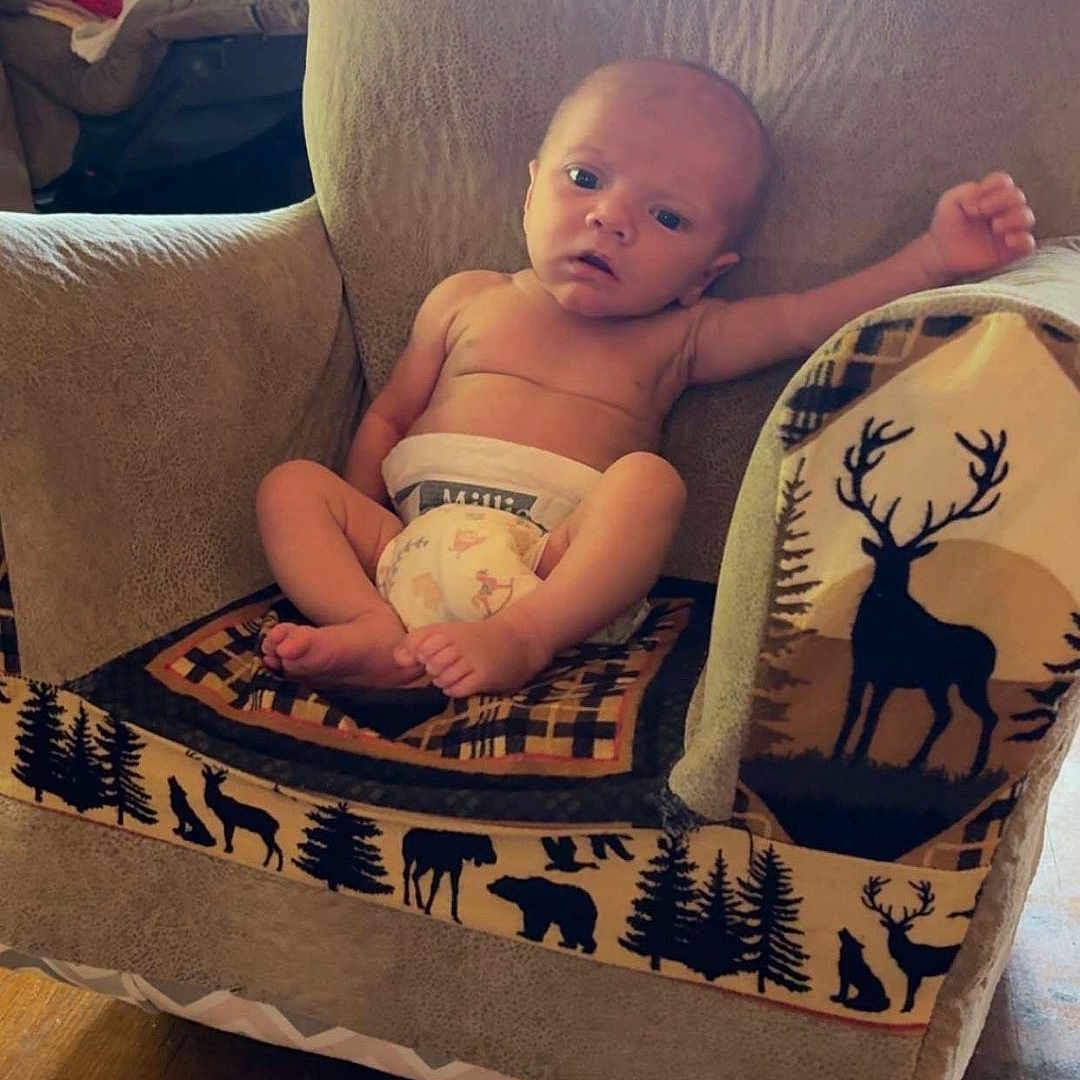 Stetson joined the competition — help win amazing prizes! baby, infant, armchair, blanket, diaper, wood_floor, indoors, furniture, child, nature_pattern, animal_print, relaxed, portrait, cute, small, person, cozy, home, lamp, window