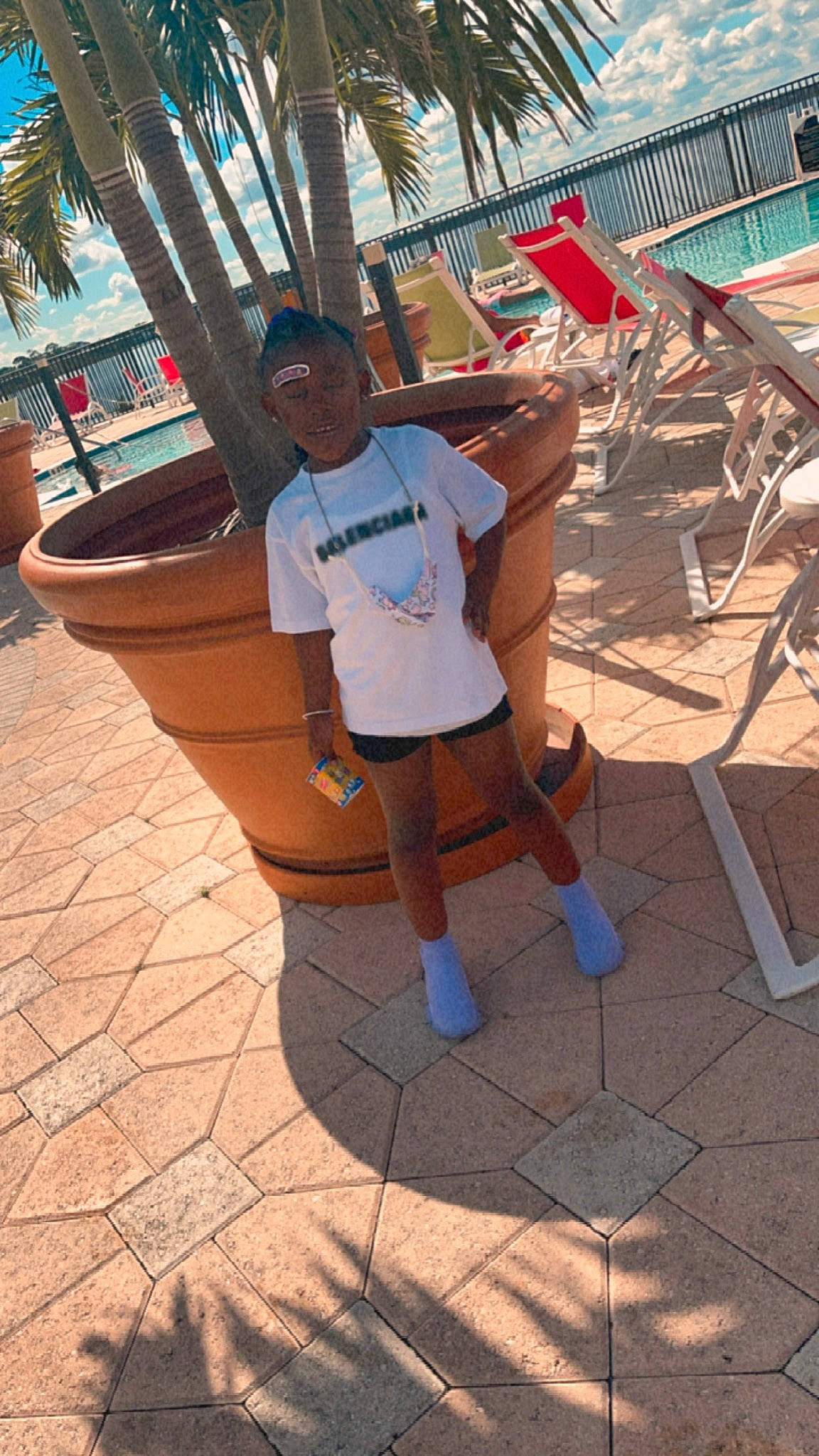 Aniya joined the competition — help win amazing prizes! chair, city, flooring, foot, fun, hat, human_leg, knee, leisure, outdoor_furniture, person, plant, recreation, shadow, shorts, sitting, t_shirt, thigh, tree, vacation