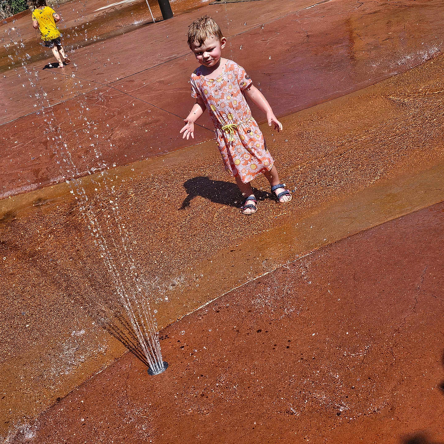 Alika is registered to the contest to win money with this photo: architecture, child, clothing, dress, face, female, footwear, fountain, girl, head, machine, person, photography, portrait, sandal, shoe, shorts, sprinkler, summer, water