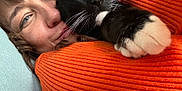 Roland joined the competition — help win amazing prizes! person, cat, tuxedo_cat, paw, whiskers, orange_sweater, cuddle, close_up, portrait, indoor, sofa, cozy, snuggle, face, nose, eye, feline, pet, happy, blanket